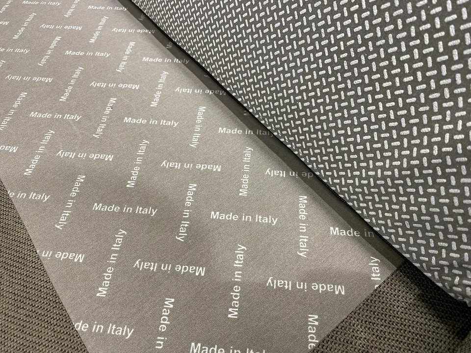 Elisir крупным планом: серая ткань с повторяющейся белой надписью Made in Italy, рядом тёмная ткань с узором из коротких белых штрихов, снизу тёмная сетчатая ткань