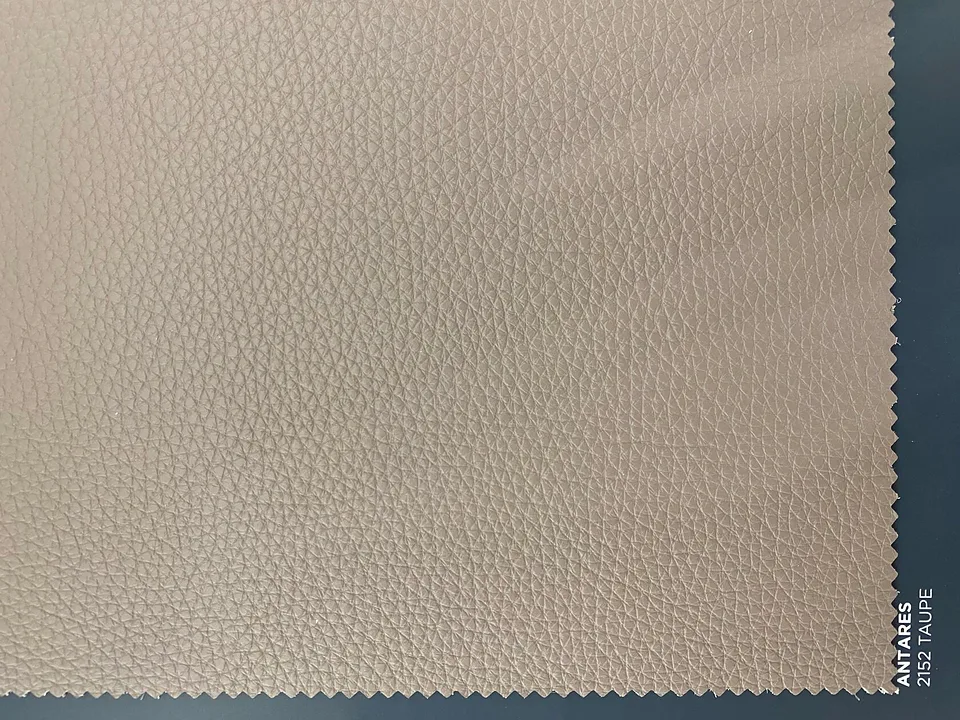 Кожа ANTARES 2152 TAUPE крупным планом: серо-бежевый образец с выраженным естественным зерном и зубчатым краем на тёмном фоне