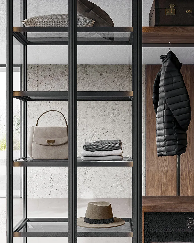 Glass all крупным планом: стеклянные полки в чёрных рамах с сумкой, свитерами и шляпой, справа пуховик на фоне панели из дерева